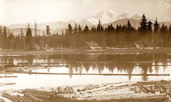Mill lake with a small lumber mill in the foreground and Mount Baker in the background, dated 1900 to 1905.