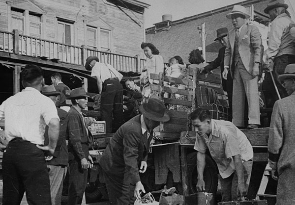 Group of Japanese Canadians arrives at an internment camp on the back of trucks.