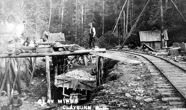 Man stands on scaffolding next to a set of railway tracks with caption reading "Clay Mines".
