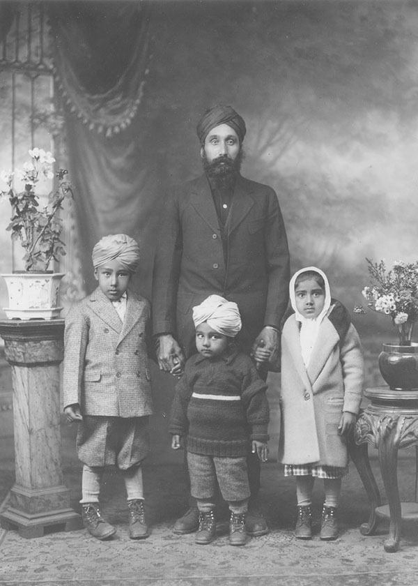 Man with a turban and long beard poses with his three small children.